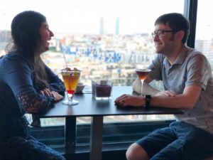 Josh and his wife in barcelona with cocktails and a city view