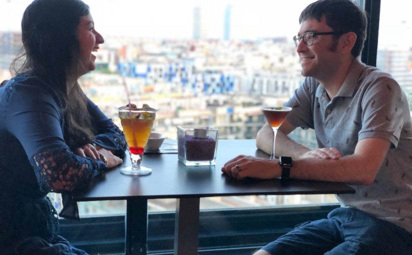 Josh and his wife in barcelona with cocktails and a city view